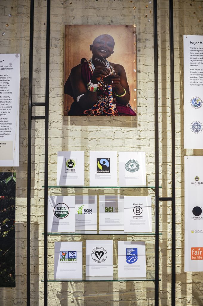 A wall and shelf containing art and logos of fair trade companies